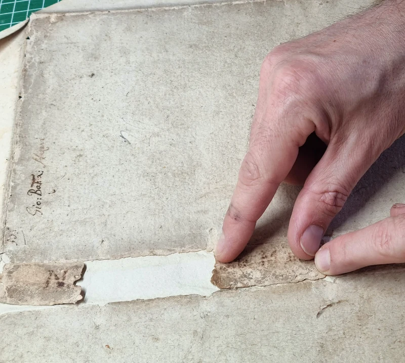 main de restaurateur posant des fragments de dos de livre ancien 