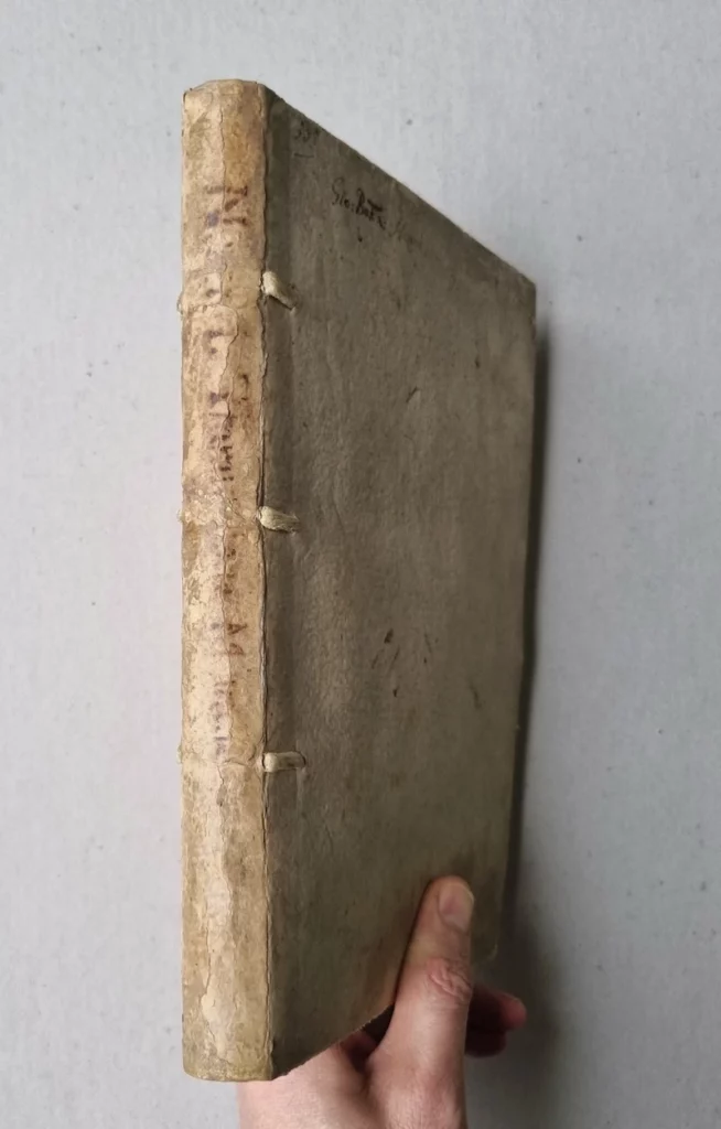 main tenant un dos restauré d'un livre ancien du 16ème siècle