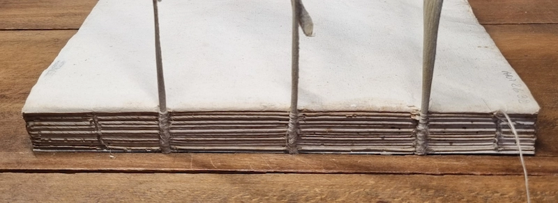 vue du dos d'un livre ancien sur un cousoir après couture terminée
